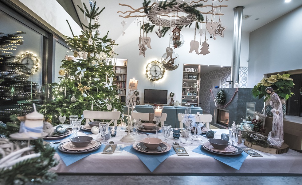 Biała zastawa na stole wigilijnym z tradycyjnym siankiem oraz przygotowane wolne miejsce dla wędrowca lub niezapowiedzianego gościa.